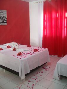 a bedroom with red walls and a bed with roses on it at Pousada Costa dos Corais in Maragogi