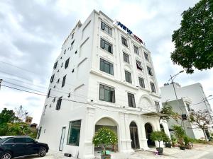 a white building with a car parked in front of it at New Hotel Phủ Lý in Trượng Trâu