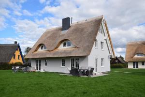 a large white house with a thatched roof at Reetdachhäuser Börgerende in Börgerende-Rethwisch