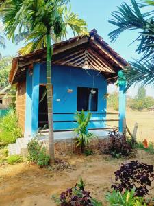 a blue house with a palm tree in front of it at Gokarna Royal Cottage in Gokarna