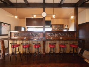 eine Küche mit einer Bar mit roten Barhockern in der Unterkunft いけだ屋 in Kōzai