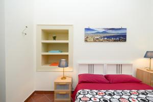 una camera con un letto rosso e una parete bianca di Residenza Santa Chiara a Napoli