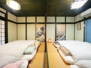 zwei Betten in einem Zimmer mit Gemälden an den Wänden in der Unterkunft いけだ屋 in Kōzai