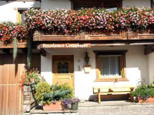 a building with a bench in front of a house with flowers at Ciasa Complojer in La Valle