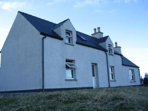 ein weißes Haus mit einem schwarzen Dach auf einem Feld in der Unterkunft Valtos 23 Isle of Lewis in 