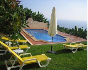 a group of chairs and an umbrella next to a swimming pool at Apartamento do Sol in Arco da Calheta