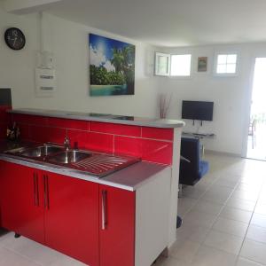 a kitchen with red cabinets and a sink at La créola BAYALOCATION in Rivière-Pilote