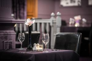 a table with glasses and a flower in a vase at Number 44 Hotel & Bar in Stonehaven