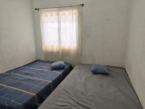 two beds in a room with a window at La casa de Alex in San Juan Opico