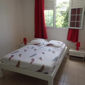 a bed with a white comforter and pillows in a bedroom at La créola BAYALOCATION in Rivière-Pilote