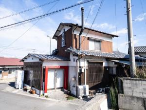 ein kleines Haus mit einer roten Tür in einer Straße in der Unterkunft いけだ屋 in Kōzai