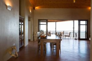 a dining room with a table and chairs and a balcony at Villas Palm Royal in Port Glaud