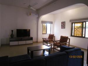 a living room with a couch and chairs and a tv at Rams Lodge in Accra