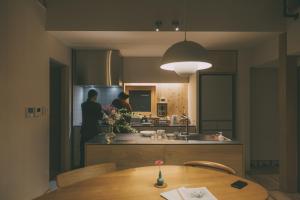 two people standing in a kitchen with a table at Peanuts Nest in Nagano