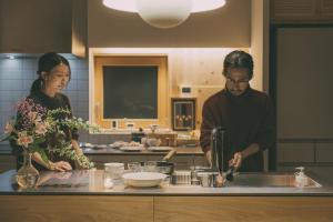 a man and woman standing in a kitchen preparing food at Peanuts Nest in Nagano