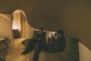 a man and woman sitting on a bed using their cell phones at Peanuts Nest in Nagano