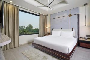 a bedroom with a white bed and a large window at Varay Grande in Ujjain +20 photos