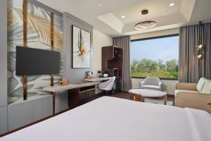 a hotel room with a bed and a desk with a monitor at Varay Grande in Ujjain