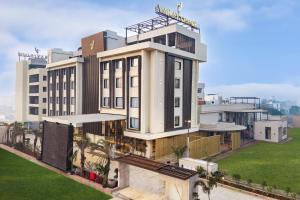 a large white building with a green lawn in front of it at Varay Grande in Ujjain