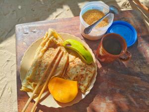 a table with a plate of food with a banana and chopsticks at Sawa Sawa Beach Hotel&Backpacks in Malindi +18 photos