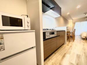 a kitchen with a microwave on top of a refrigerator at TIC HOTEL Hisayaodorisakae in Nagoya