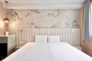 a bedroom with a white bed and a wall with blue flowers at 芙蘿拉萃旅 in Taitung City