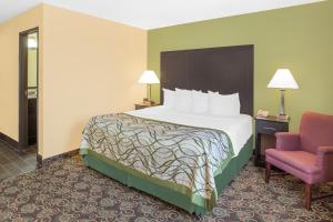 a hotel room with a bed and a chair at Baymont by Wyndham Holland in Holland +26 photos