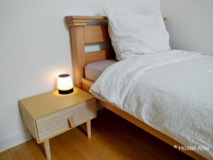 a bed with a nightstand next to a bed with a lamp at Hostel Alfar in Sarajevo