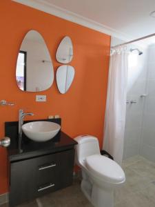 ein Bad mit einem WC, einem Waschbecken und einem Spiegel in der Unterkunft Hotel Lleras Premium #1 in Medellín