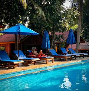a person laying in lounge chairs next to a swimming pool at PawPaw Resort in Lamai