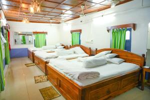 four beds in a room with green curtains at Banalata Resort in Jaypur +66 photos