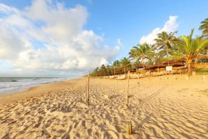 a beach with palm trees and a hammock in the sand at Grand Palladium Imbassaí Resort & Spa - All Inclusive in Imbassai