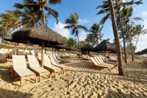 a group of chairs and umbrellas on a beach at Grand Palladium Imbassaí Resort & Spa - All Inclusive in Imbassai
