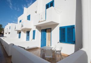um edifício branco com persianas azuis e mesas numa varanda em Residence Blu Mare em San Vito lo Capo