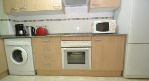 a kitchen with a washing machine and a microwave at Apartamentos Inbesal in La Pineda