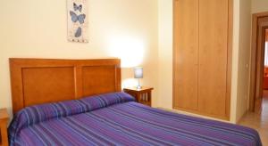 a bedroom with a large bed with a wooden headboard at Apartamentos Inbesal in La Pineda +23 photos