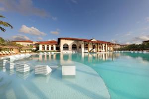 a large swimming pool with white chairs in front of a building at Grand Palladium Imbassaí Resort & Spa - All Inclusive in Imbassai