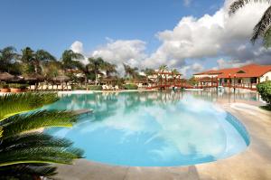 a large swimming pool at a resort with palm trees at Grand Palladium Imbassaí Resort & Spa - All Inclusive in Imbassai