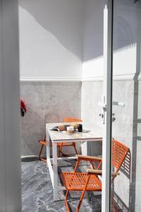 a dining room with a white table and orange chairs at Nghia Lan Hotel - Dalat Market in Da Lat