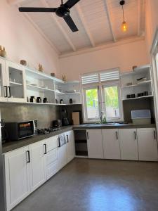 a kitchen with white cabinets and a ceiling fan at Villa Mario in Unawatuna