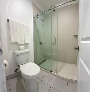 a bathroom with a toilet and a glass shower at La Casa Motel, Los Angeles - Burbank Airport in Sun Valley