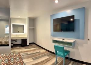 a room with a desk and a tv on a wall at La Casa Motel, Los Angeles - Burbank Airport in Sun Valley +15 photos