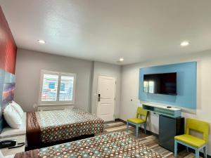 a hotel room with two beds and a flat screen tv at La Casa Motel, Los Angeles - Burbank Airport in Sun Valley