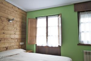 Dormitorio verde con 2 camas y ventana en Casa de Aldea El Sol, en Poo de Cabrales