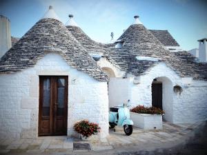 
a white house with a blue roof and a white door at Trulli Holiday Albergo Diffuso in Alberobello
