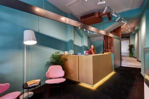 a woman standing at a counter in an office at Colors Urban Hotel Thessaloniki in Thessaloniki
