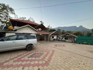 a white car parked in front of a building at New Hambala Homestay in Attigundi