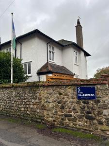 a house behind a stone wall with a sign at Boutique Rooms at The Ellesmere in Hornsea