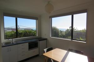 a kitchen with two large windows and a table with chairs at Affordable On Arun in Oamaru