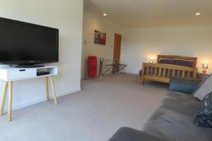 ein Wohnzimmer mit einem Flachbild-TV und einem Sofa in der Unterkunft Affordable On Arun in Oamaru